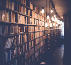 Image of library stacks lit by numerous hanging lightbulbs.