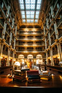 Photograph of a man sitting at a desk with books at the George Peabody Library in Baltimore.