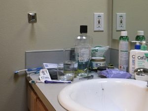Bathroom counter with various toiletries strewn about, and sink/basin.