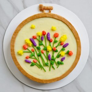 The final embroidery cake, with a gold screw at the top and yellow, pink, and purple flowers