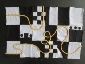 Black and white patchwork textile with random pattern. Yellow curving line design