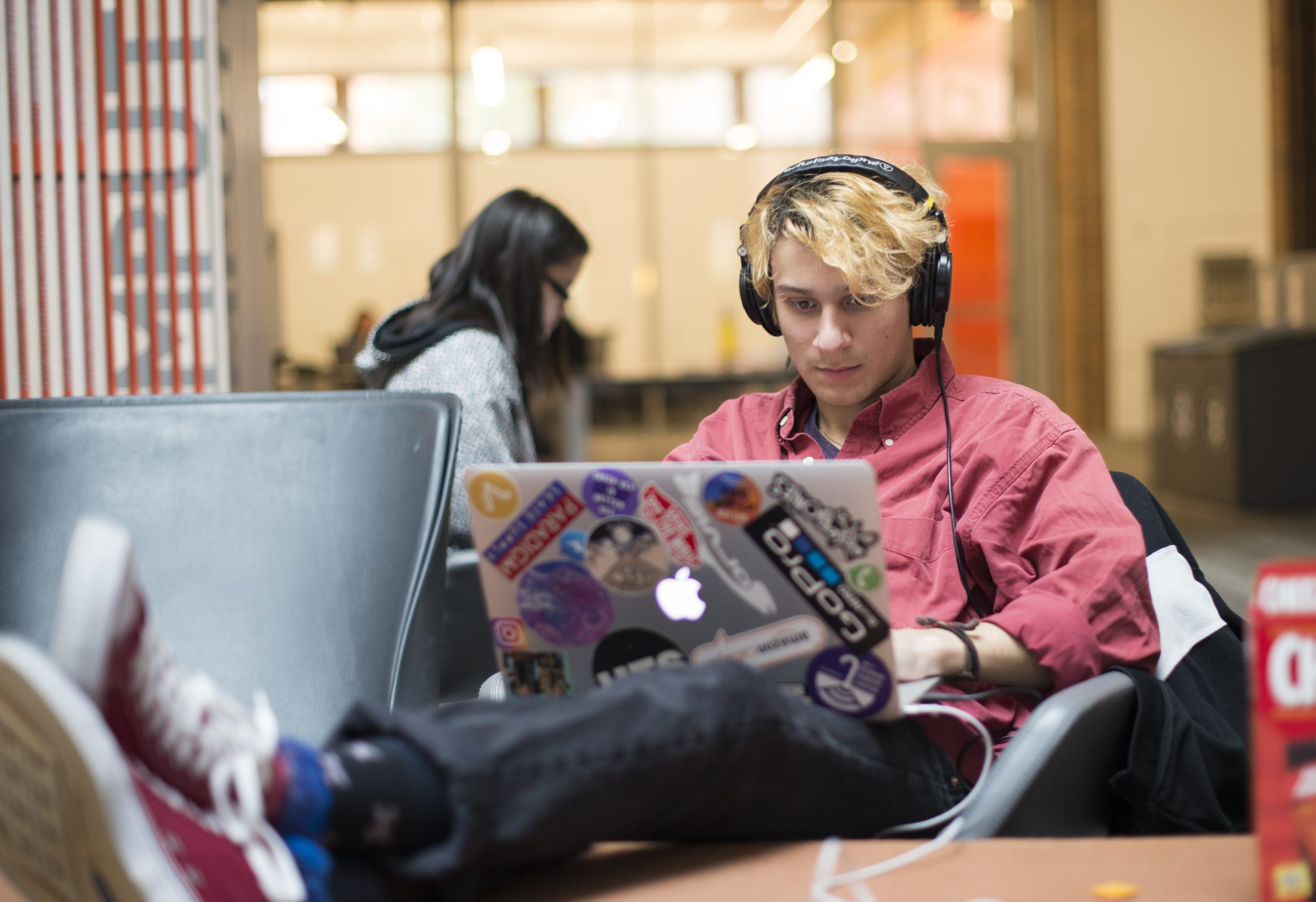 Student with laptop and headphones studying in Odegaard Library.