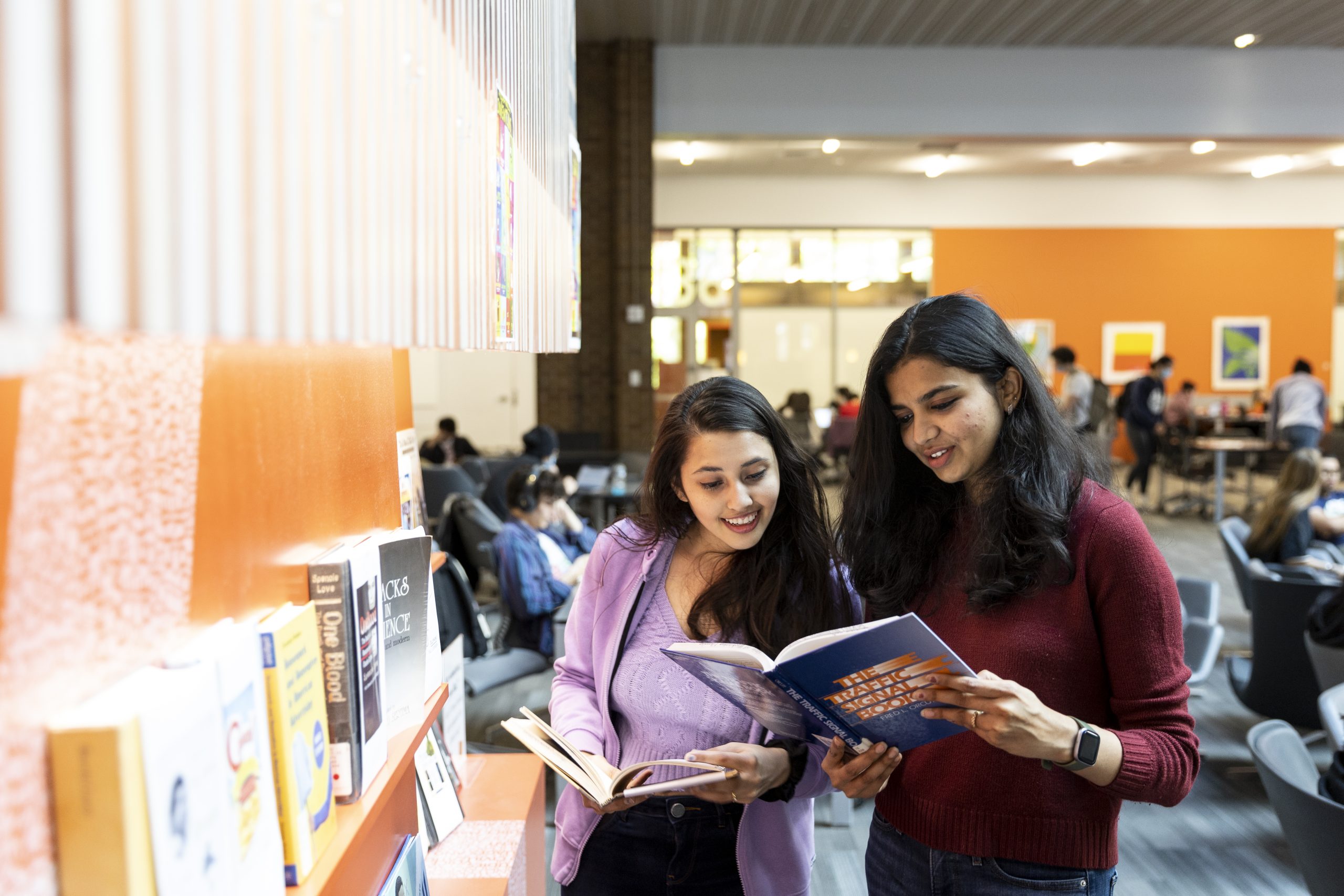 Two students looking at a book in Odegaard Library.
