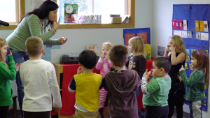 Adult instructing preschoolers to touch their nose