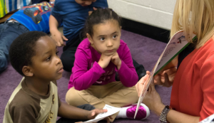 Children listening as adult reads book and shows them the pictures