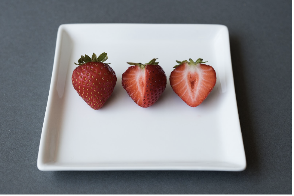 Three strawberries sitting on a white plate.