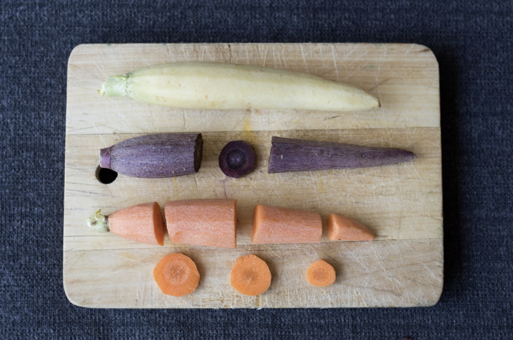Three carrots on a cutting board with some sections removed.