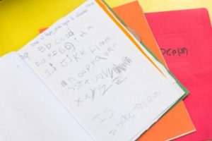 open booklet with a child's writing practice of different letters on the page.