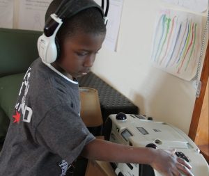 Young boy wearing headphones clicking a button on a cd player.