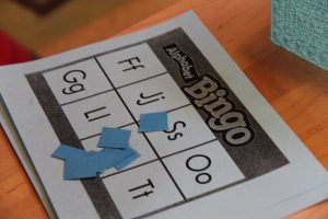 Picture of bingo card with letters on it and blue pieces to mark each space for alphabet bingo.