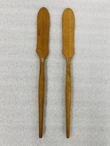 Two rice spoons laying side by side on a table. The top of the spoon starts wide and becomes narrow as you go down the handle.