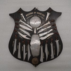 Plaque with 18 swords/knives, a shield and a spear, and an Agong