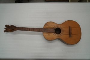 A wooden instrument with nine strings, a figure eight body shape, and a round central sound hole