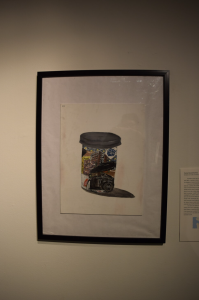 Charisse's art piece titled "Grandpa Joe", framed painting of a film canister featuring a camera and other trinkets inside of it.