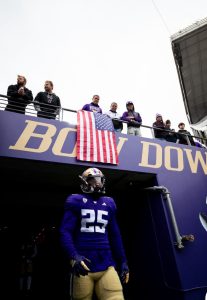 A football player exits the tunnel. He stands under an American flag.