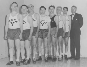 Historic photo of the Seattle Y basketball team from 1940-1944, showcasing eight players and a coach in uniform.