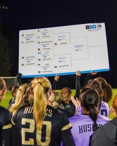 Female soccer players holding a large poster of a tournament bracket