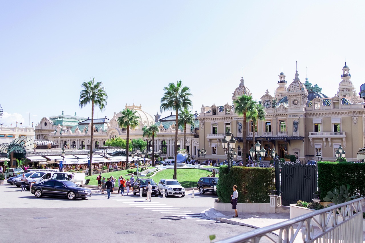 Exterior view of the Monte Carlo Casino in Monaco, showcasing its ornate architecture with grand arches, decorative sculptures, and an elegant facade under a bright sky